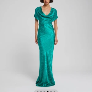 Grön långklänning i satinlook - Säljer en smaragdgrön långklänning med glansig satinlook och diskret prickigt mönster. Klänningen har draperad v-ringning och korta ärmar, figurnära passform och faller snyggt längs kroppen. Perfekt för bal eller festliga tillfällen. Endast använd 1 gång!! Nypris 2700