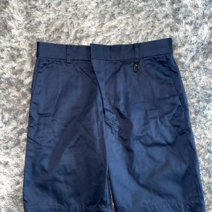 Marinblå shorts från Louis Vuitton - Snygga marinblå shorts från Louis Vuitton, tillverkade i Italien. Klassisk design med bälteshällor, dragkedja och exklusiva metalldetaljer med logga. Perfekta för dig som vill ha en stilren och lyxig look i sommar. Materialet är mjukt och bekvämt, troligtvis bomull.