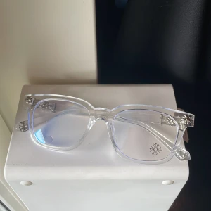 Blue light glasögon från Chrome Hearts - Säljer ett par riktigt snygga glasögon från Chrome Hearts med transparent båge och rektangulär form. Bågarna har silverdetaljer med ikoniska kors och logga på glaset. Tillverkade i Italien och ger en clean och exklusiv vibe. Rensar i garderoben och hittade denna har tyvärr tappat bort lådan och förpackningen men glasögonen är fortfarande i topp skick