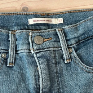 Levi's 311 shaping skinny jeans blå - Säljer ett par klassiska Levi's 311 shaping skinny jeans i mellanblå tvätt. Modellen är högmidjad med skinny passform och har fem fickor samt dragkedja och knapp framtill. Perfekta jeans för dig som gillar en smickrande och bekväm stil.