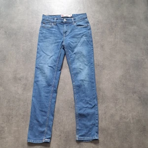 Levi's 502 Regular Taper jeans blå - Säljer ett par klassiska blå Levi's 502 Regular Taper jeans. De har en snygg, rak passform med lätt avsmalnande ben och fem fickor. Jeansen är i mjukt denimtyg och har Levi's ikoniska läderpatch bak i midjan. Perfekta för en chill och stilren look.