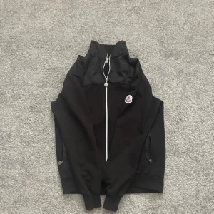 Svart Moncler jacka i m - Svart stilig jacka från märket moncler med den ikoniska loggan på armen. Längden på tröjan är 170cm, går självklart ner i pris om det behövs tar även byten😀
