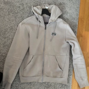 Grå EA7 Emporio Armani kofta - Stilren grå Armani kofta perfekt för lite kyligare sommar kvällar. Endast använd några få gånger Storlek XS men passar ändå väldigt bra som S.
