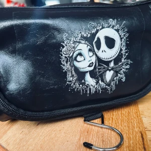 Stor necessär med vintage-motiv! - Stor necessär i fuskskinn med "The Nightmare before christmas"-motiv med många fack, dragkedja, handtag och krok för upphängning. Mått: 15 x 15 x 25 cm. Oanvänd.