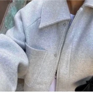 Beige kappa i ullmix  - En snygg beige kappa i storlek m från Zink. En stor ficka framtill och två fickor på sidorna. 