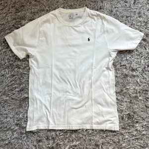 Vit t-shirt från Polo Ralph Lauren - Säljer nu en  vit t-shirt från Polo Ralph lauren på grund av att den inte kommer till användning längre storleken är 170 men den sitter som M. Har du några funderingar är de bara att fråga.