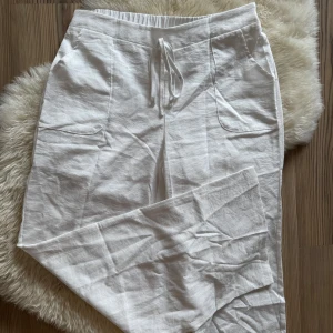 Vita linnebyxor med snörning - Snygga vita linnebyxor med inbyggda shorts så dem inte är genomskinliga. Byxorna har två fickor framtill och är tillverkade i ett luftigt linnematerial, perfekta för varma dagar. Aldrig använda 