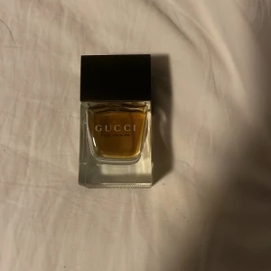 Gucci Pour Homme Eau de Toilette - Säljer en elegant Gucci Pour Homme Eau de Toilette. Flaskan har en stilren design med en fyrkantig form och svart lock. Doften är klassisk och maskulin, perfekt för den stilmedvetna mannen. En exklusiv parfym som ger en sofistikerad touch till din doftgarderob.