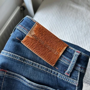 Blå jeans från Jacob Cohen - Snygga blå jeans från Jacob Cohen med klassisk femficksdesign och en stilren läderpatch baktill. Jeansen har en normal passform och är tillverkade i högkvalitativt denim. Perfekta för en avslappnad stil.