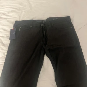 Svarta jeans från Armani Jeans - Snygga svarta jeans från Armani Jeans med en klassisk femficksdesign. De har en regular passform och är perfekta för en stilren look. Märkesetikett på baksidan och diskreta detaljer gör dem till ett måste i garderoben. Aldrig använd, prislappen kvar. Mycket bra skick.