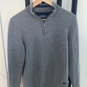 Grå tröja från Jean Paul - Säljer en stilren grå tröja från Jean Paul i mjuk merinoull. Tröjan har en praktisk dragkedja vid halsen och långa ärmar. Perfekt för kyligare dagar! Krympt så sitter som en S