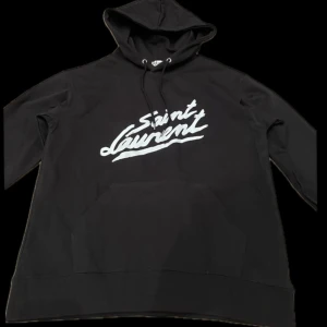 Hoodie - Tja! Säljer nu denna snygga svarta hoodien från Saint Laurent med vit logga på bröstet. Den är använd ett par gånger och är i storlek M. Vid snabb affär kan jag gå ner i pris! Mer information finns i dm! 