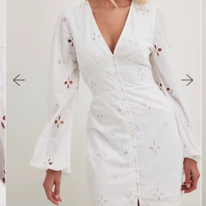 Vit klänning med blommigt mönster - Säljer en söt vit klänning med blommigt mönster och v-ringning. Klänningen har långa ärmar och knappar framtill. Perfekt för studenten 