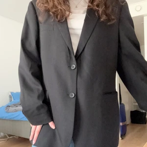Svart kavaj - Snygg svart kavaj med två knappar framtill och två fickor. Perfekt att använda som oversized. Köpte den begagnad men har knappt använt den. 