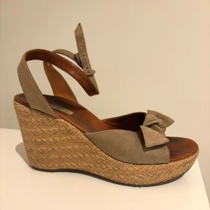 Somriga klack sandaler  - Fina sandaler med kilklack och en rosett framtill. Sandalerna har en justerbar rem runt ankeln och är tillverkade i mocka med en flätad sula. Det står att de ska vara storlek 38 men de är för stora för mig som brukar bära storleken så jag skulle uppskatta dem som 39💕de är smått skavda framtill