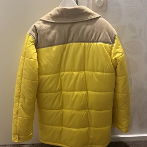 Gul dunjacka från Björn Borg - Säljer en jätteskön gul dunjacka från Björn Borg med beige detaljer på axlarna och kragen. Jackan har en dragkedja och knappar framtill samt långa ärmar. Som ger dig perfekt skydd för kyliga dagar!…Som man ser på bild har den väl tagits hand om. Jackan köptes från själva butiken för 4500kr. mitt pris 2950kr, är ej hugget i sten. Mvh Emilia