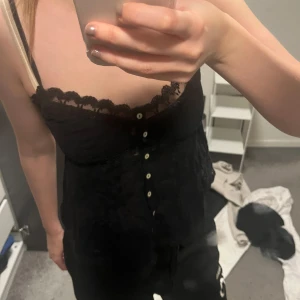 Svart spetslinne - Säljer ett svart linne med spetsdetaljer och knappar framtill från Zara 