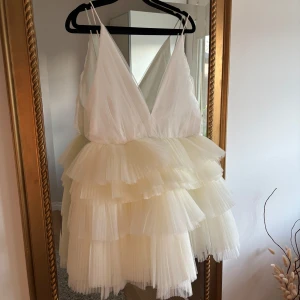 Vit volangklänning med djup urringning - Säljer en superfin vit klänning med flera lager av volanger och en djup v-ringad urringning. Klänningen är ärmlös och har tunna axelband. Skulle varit min studentklänning i sommar men den va tyvärr för stor, kostar nypris 1799kr❤️