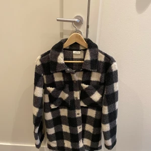 Svart och vit rutig jacka från KappAhl - Säljer en snygg och mysig svart och vit rutig jacka från KappAhl. Storlek 170, funkar som Xs