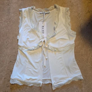 Vit spetstopp NA-KD - en jättesöt offwhite topp från NA-KD med fina spetsdetaljer och knytning framtill. perfekt nu till vår och sommar. nyskick, önskar jag kunde behålla men passar inte mig tyvärr