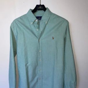 Grön skjorta från Ralph Lauren - Snygg skjorta från Ralph Lauren i storlek M. Skjortan är i nyskick och ör ett utmärkt val inför sommaren! Nypris är 1599kr och mitt pris är 399kr! Vid frågor tveka inte på att höra av er!!!