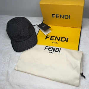 Svart keps från Fendi - Snygg svart keps från Fendi med ett diskret mönster. Kepsen har en klassisk design med justerbar passform och är perfekt för en stilren look.