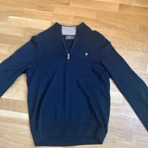 Mörkblå merinoulltröja från Morris - Säljer en stilren mörkblå tröja från Morris i 100% merinoull. Tröjan har en dragkedja vid halsen och ett litet broderat emblem på bröstet. Tröjan är storlek M men skulle passa en S  Kom med frågor. Priset är ej hugget i sten!!