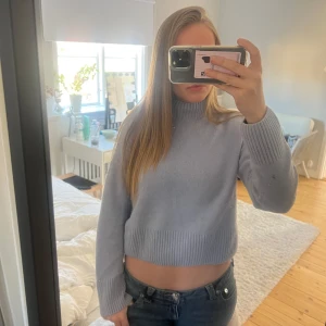 Ljusblå croppad stickad tröja - Säljer en ljusblå croppad stickad tröja med ribbade detaljer vid hals och ärmslut. Perfekt för en stilren och avslappnad look. Passar bra till jeans eller kjol till sommaren. 