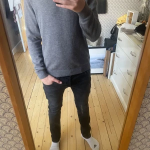 Grå tröja från These Glory Days - Säljer en stilren grå tröja från These Glory Days i Superior Merino. Tröjan har en klassisk rund hals och långa ärmar, perfekt för en avslappnad look. Den är mjuk och bekväm, idealisk för kyligare dagar. 