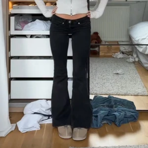 Svarta bootcut  jeans - Snygga svarta bootcut jeans med låg midja och knappar framtill. Perfekta för en trendig look. Passar bra till både sneakers och klackar. 🤍 skriv för egna bilder strlk 26/32 men har förkortat dem💕helt nya Annars därför är priset så lågt 💗