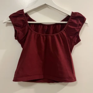 Vinröd topp från Brandy Melville - Säljer en söt cropped vinröd topp från Brandy Melville. Toppen har korta ärmar och en rundad halsringning. 