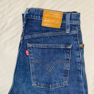 Levi's Ribcage Straight Jeans - Snygga Levi's Ribcage Straight jeans i klassisk blå denim. De har en hög midja och raka ben. De är lite för stora för mig i midjan så därför behöver jag tyvärr sälja dem 💙Passar både till vardags som till fest 🪩