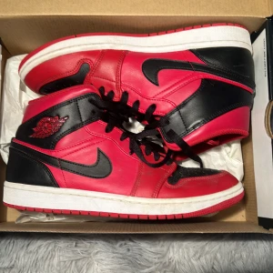 Nike Air Jordans i rött och svart - Snygga Nike Air Jordans i en klassisk röd och svart färgkombination. Skorna har en ikonisk design med svart snörning och den välkända Air Jordan-loggan på sidan. Perfekta för dig som vill ha en stilren och sportig look. Nästan helt oanvända 