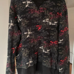 Hope Mönstrad tröja Large herr - Säljer en cool tröja från Hope med ett unikt mönster i svart, rött och vitt. Tröjan har långa ärmar och en avslappnad passform. Tillverkad i Portugal.