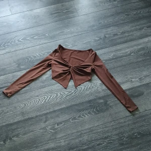 Brun knuten topp med öppen mage - Toppen är i storlek S men köpt på petit avdelning så kuporna är väldigt små. Jag är en S/XS och om jag sträcker upp armarna mot taket så åker toppen upp över brösten. Aldrig använt.
