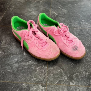 Rosa och gröna sneakers från Puma - Snygga rosa sneakers från Puma med gröna detaljer och gummisula. Skorna har snörning och är tillverkade i mocka. Funkar både ute men även som jag har använt dem för futsal🤗