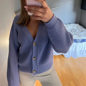 Blå stickad kofta - Säljer en mysig blå stickad kofta med stora knappar framtill. 