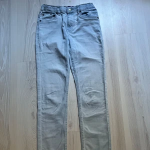 Ljusblå jeans från Levi's - Säljer ett par ljusblå jeans från Levi's med klassisk femficksdesign och knappgylf. Perfekta för en avslappnad stil. Levi's logga syns på bakfickan.