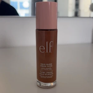 e.l.f. Halo Glow Liquid Filter - e.l.f. Halo Glow Liquid Filter är en flytande produkt som ger huden en strålande lyster. Den kommer i en elegant flaska med rosa lock och är perfekt för att skapa en glödande finish. Den är endast testad på handen. Den är i färgen 6 tan/deep