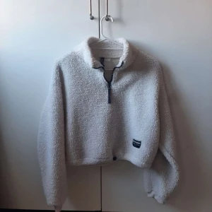 Vit fleece tröja med dragkedja - Mysig vit fleece tröja med halv dragkedja och en liten etikett på framsidan. Perfekt för kyliga dagar med sin fluffiga och varma design. Tröjan har en croppad passform och långa ärmar🌸❤️
