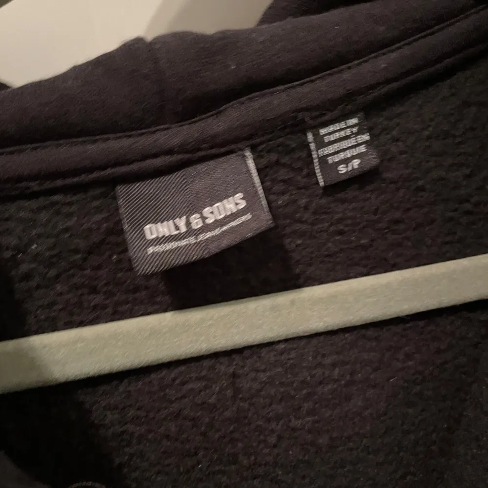 Säljer en svart hoodie från Only & Sons med dragkedja och huva. Den har långa ärmar och snörning vid huvan. Perfekt för en stilren look. Helt oanvänd! Bara höra av sig vid frågor!. Neuletakit & Villapaidat.