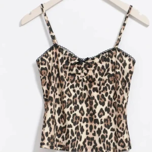 Leopardmönstrad linnetopp - Snygg leopardmönstrad linnetopp med smala axelband och en söt rosett framtill. Toppen har en fin spetsdetalj längs kanten och är perfekt för en trendig look.