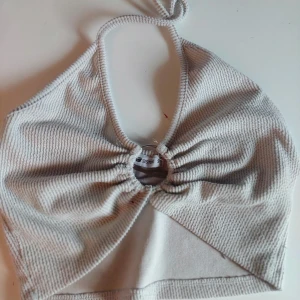 Grå ribbad halterneck topp - Snygg grå ribbad halterneck topp från New yorker. Toppen har en knytning i nacken och en dekorativ ringdetalj framtill som ger en unik look. Perfekt för varma dagar eller som en del av en lager-på-lager outfit. Den har en silver ring i mitten ♡