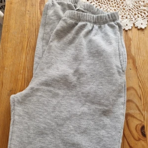 Grå mjukisbyxor med resårmidja - Mysiga grå mjukisbyxor med resår i midjan och sidofickor. Perfekta för chill dagar eller när du vill vara extra bekväm. Tillverkade i mjukt material som känns skönt mot huden.