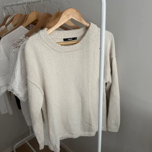 Créme färgad stickad tröja från Bik Bok - Mysig créme färgad stickad tröja från Bik Bok med rund halsringning och lång ärm. Tröjan har en lätt textur och är perfekt för lager-på-lager under kyligare dagar. Enkel och stilren design som passar till det mesta.