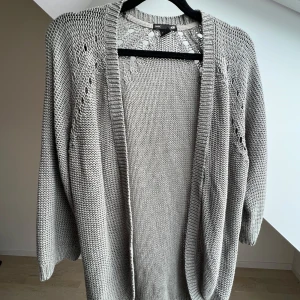 Grå/grön stickad kofta från H&M - Stickad kofta från H&M storlek M. Några större öglor på baksidan längre ner som säkert går att fixa