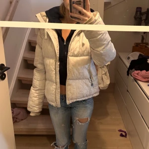 Vit pufferjacka - Vit pufferjacka från Vflame perfekt för vintern, det går att ta av ärmarna så det blir en väst den är även justerbar i midjan om man vill ha den tightare kan ses på bild 2, det är högkrage med inbyggd balaclava. Det är unisex, har ett till inlägg med denna jacka när min kille har den som väst.