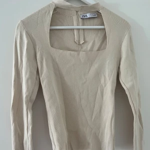 Beige långärmad topp från Zara - Perfekta festtoppen som är stilren beige långärmad topp från Zara med fyrkantig ringning och lätt ribbad struktur. 