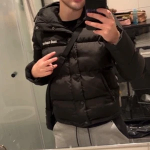 Svart pufferjacka från Saint Denim - Säljer min puffer jacka från mobnation väldigt unik jacka , denna modellen säljs inte mer på hemsidan , köpte den för 1700 med frakt , varm till vintern , Jackan är vadderad och har en klassisk, boxig passform med dragkedja framtill. Perfekt för kalla dagar när du vill hålla stilen enkel och clean.