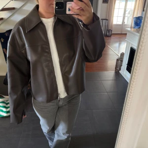 Brun skinnjacka från Carin Wester - Säljer en brun skinnjacka från Carin Wester med oversized passform och stora slag. Jackan har dragkedja framtill och är tillverkad i ett slätt, syntetiskt skinnmaterial. Perfekt för dig som gillar en clean och stilren look. Perfekt nu till hösten. 
